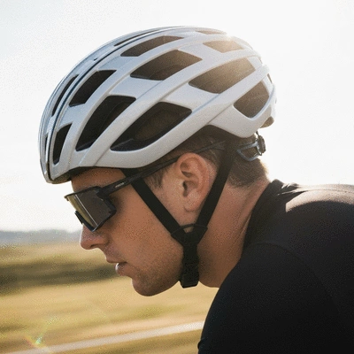 Cyclist wearing a modern, well-fitted road cycling helmet, focus on safety and comfort, bright outdoor setting