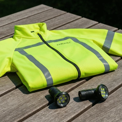 High-visibility cycling jacket with reflective strips and LED bike lights on a wooden table